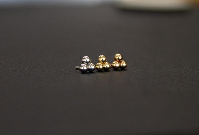 Curated stud earrings in silver and gold on a dark surface