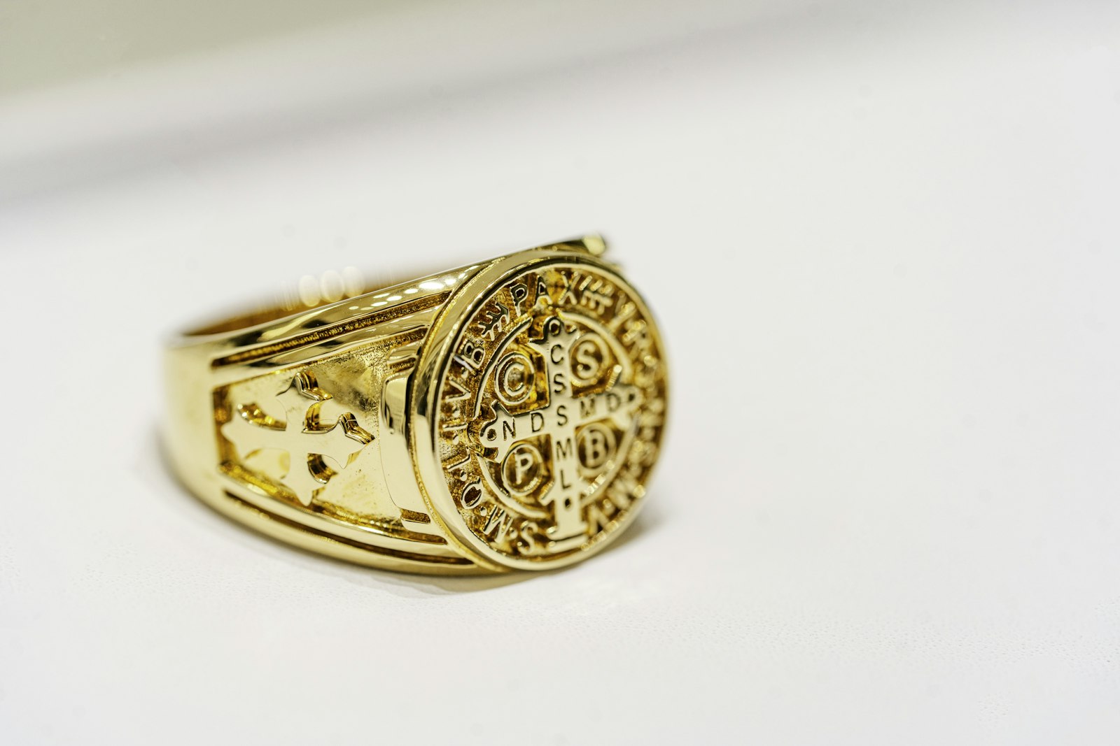 Close-up product photo of an engraved gold signet ring on a clean white surface