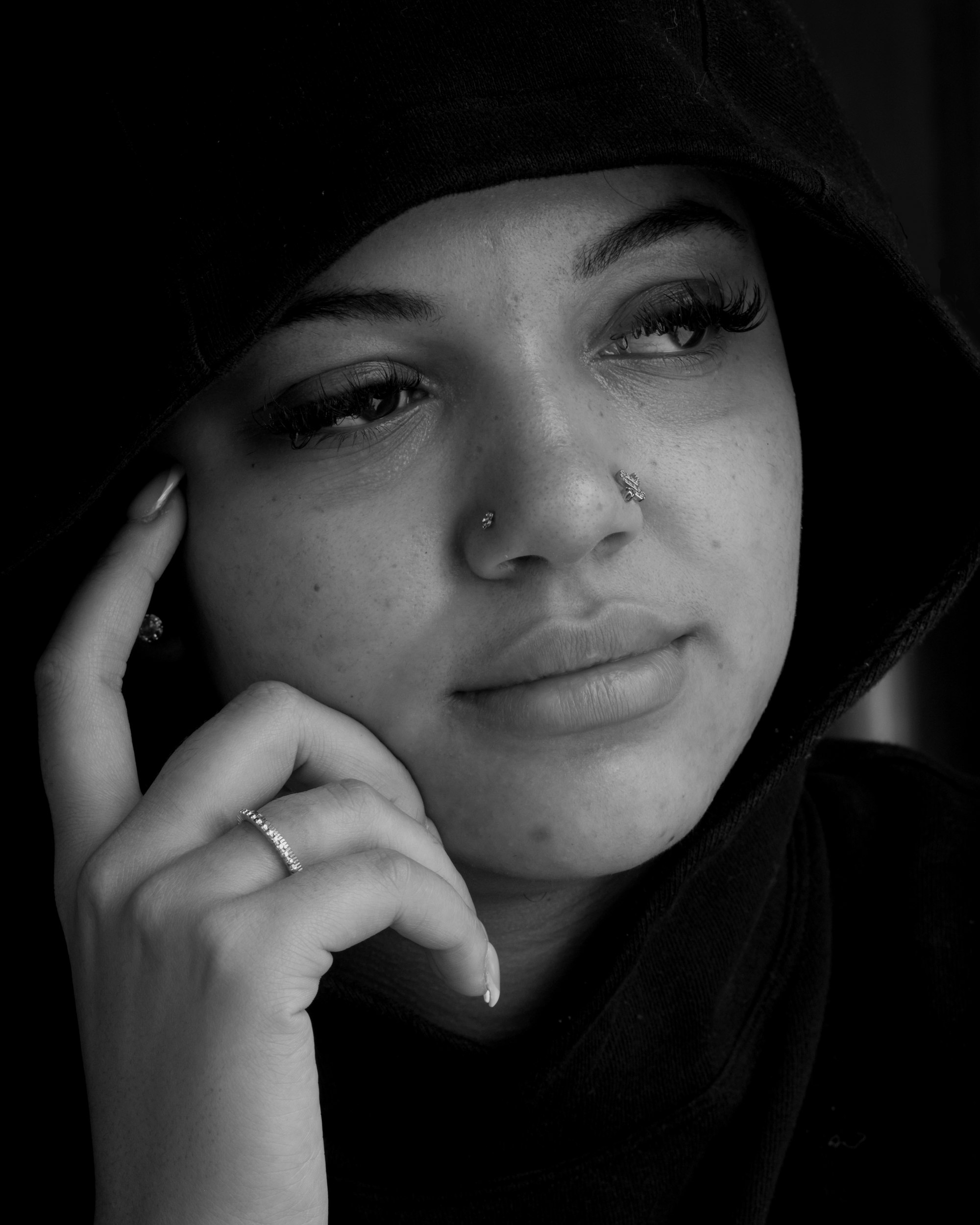 Black-and-white portrait of a woman in a hoodie with a delicate nose stud piercing