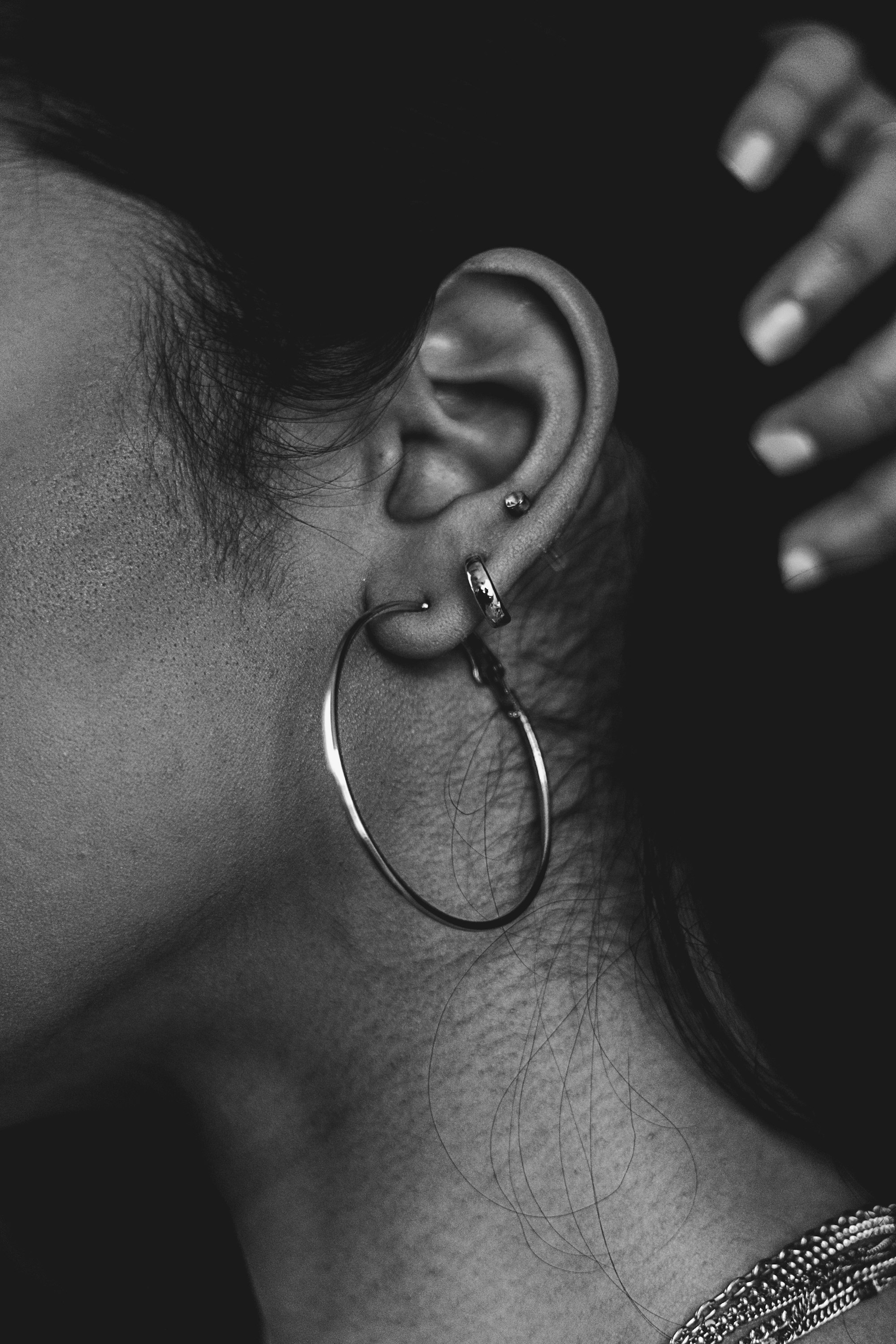 Close-up of an ear with curated cartilage piercings against a soft neutral background