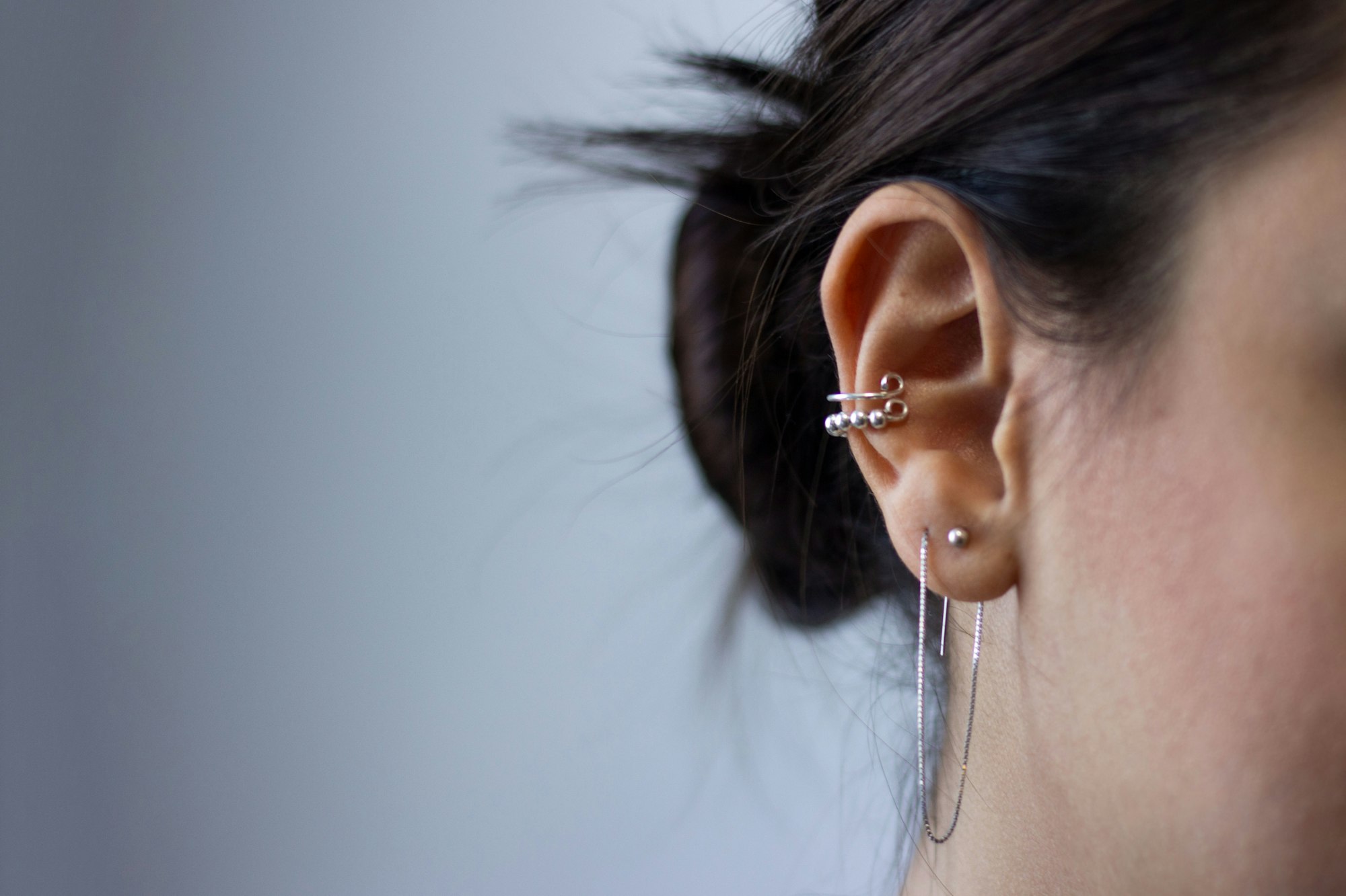 Warm-toned close-up of a nose piercing with a slim silver ring