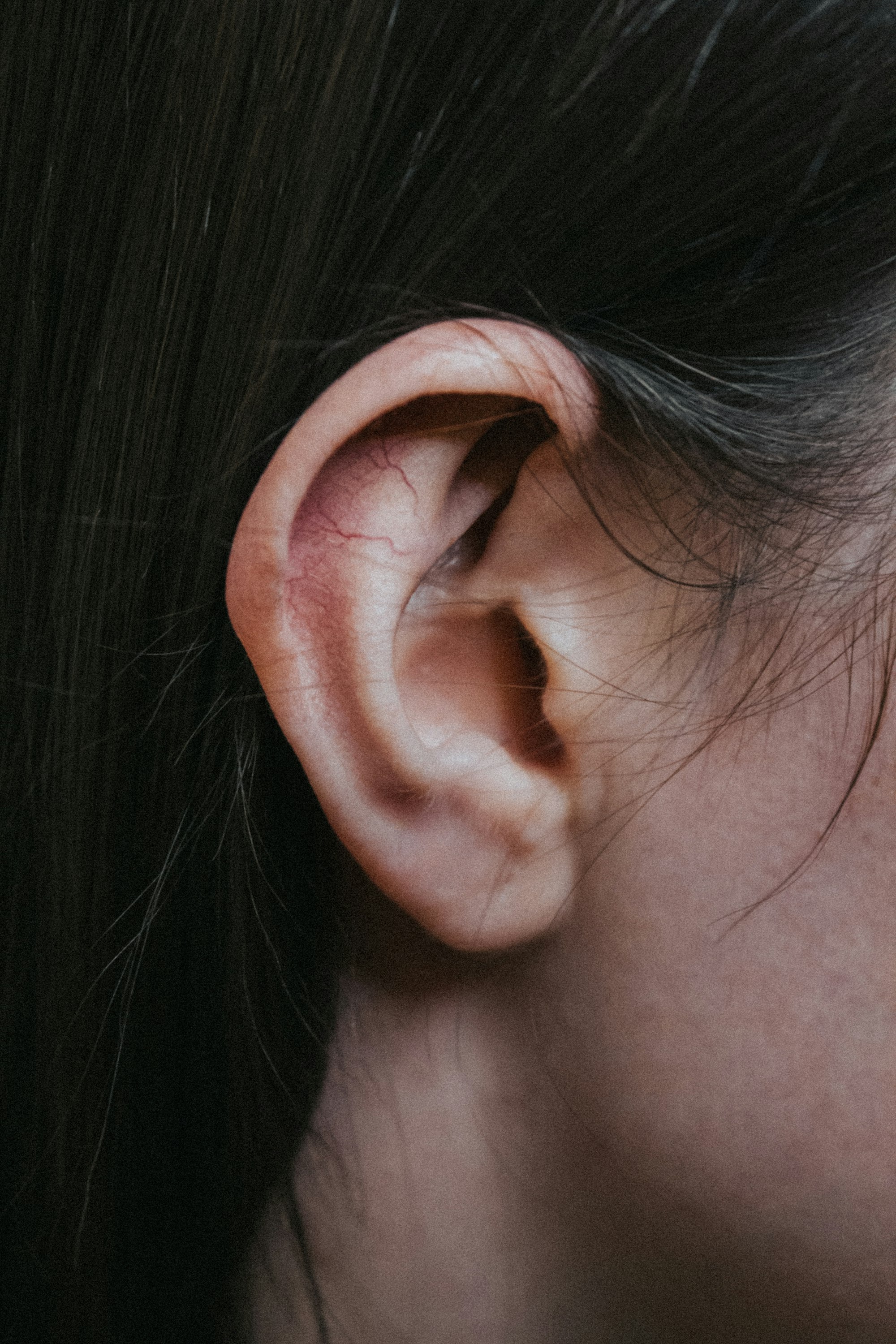 Minimalist close-up profile of an ear against a plain light background