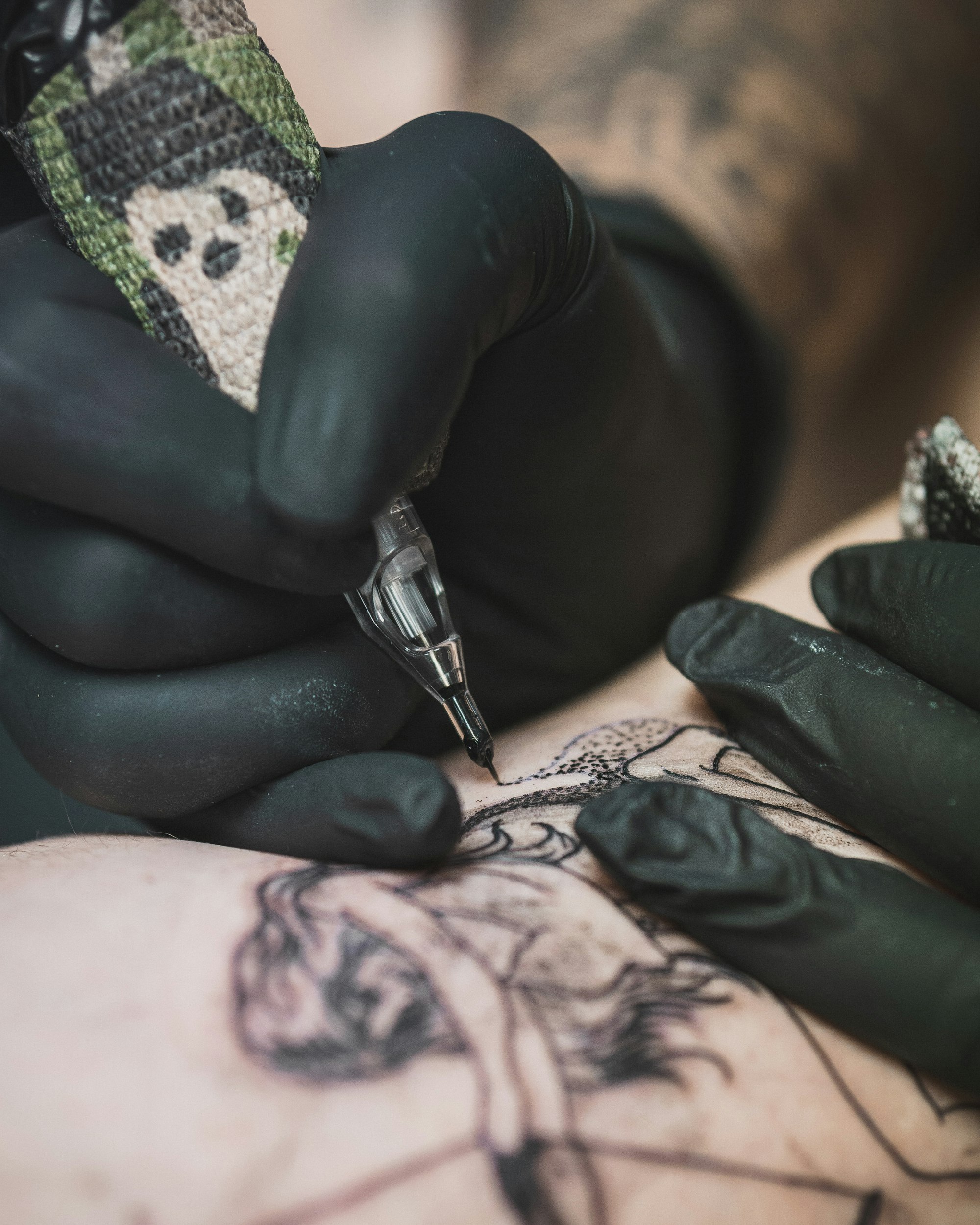 Overhead shot of a tattoo artist outlining a large-scale piece on a client’s arm