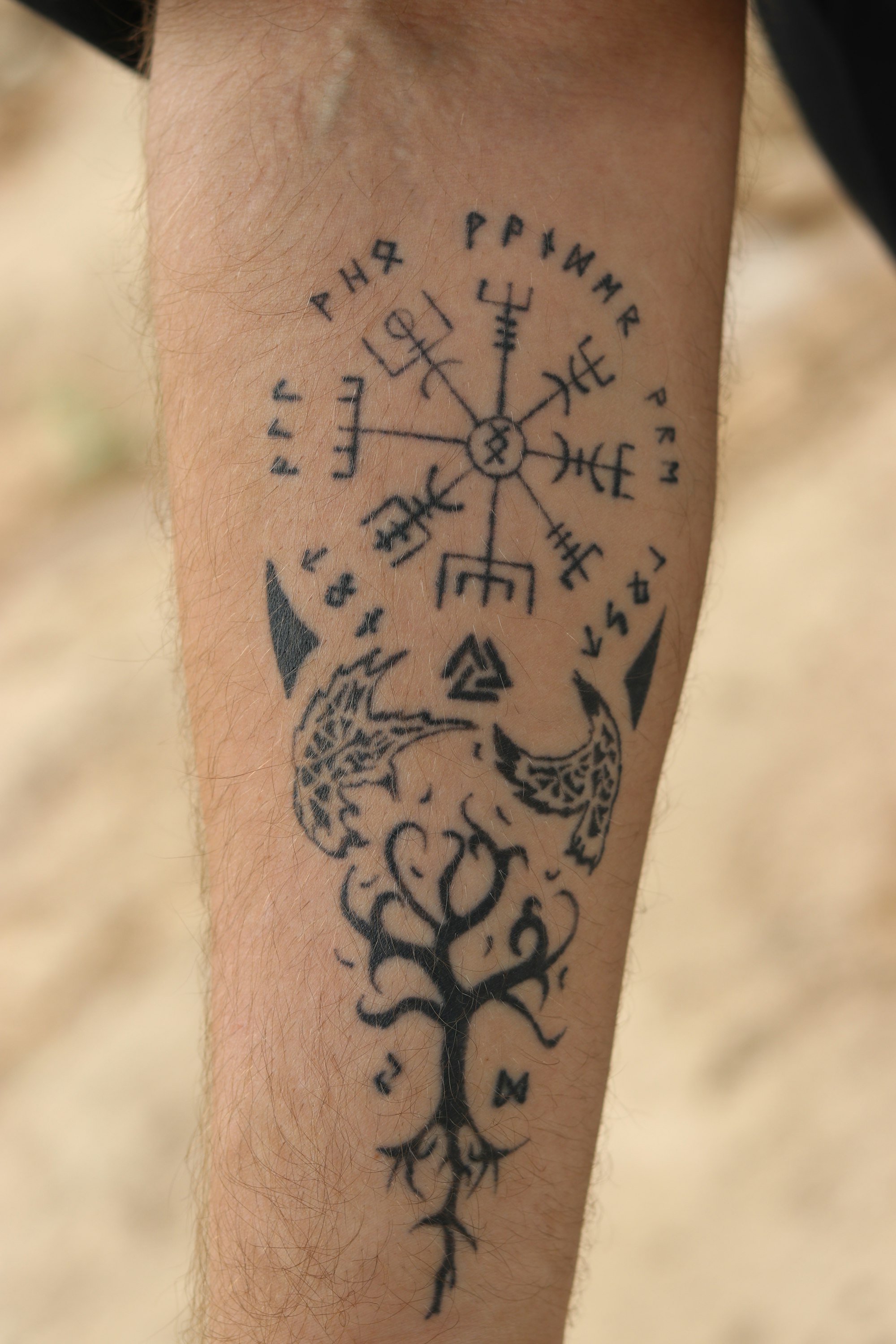 Black-and-white close-up of a fine-line botanical tattoo on a forearm
